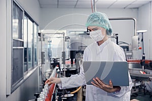 Food and drink industry staff worker working at conveyor belt production line machine in beverage factory with clean and hygiene