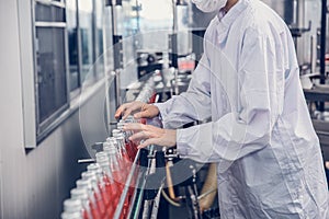 Food and drink industry staff worker working at conveyor belt production line machine in beverage factory with clean and hygiene