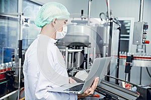 Food and drink industry staff worker working at conveyor belt production line machine in beverage factory with clean and hygiene