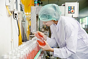 Food and drink industry staff worker working at conveyor belt production line machine in beverage factory with clean and hygiene