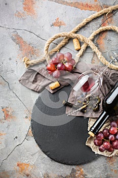 Bottle, corkscrew, glass of red wine, grapes on a table