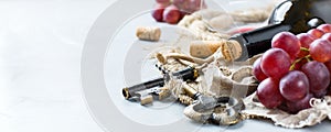 Bottle, corkscrew, glass of red wine, grapes on a table