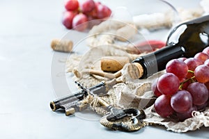 Bottle, corkscrew, glass of red wine, grapes on a table