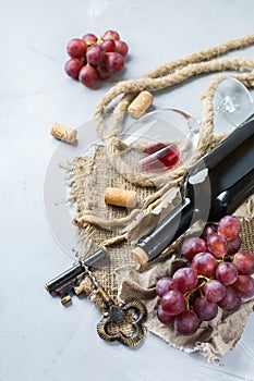 Bottle, corkscrew, glass of red wine, grapes on a table