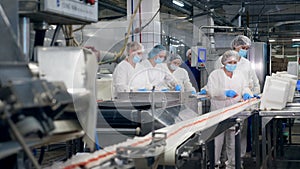 Food factory workers packing products from a moving line.