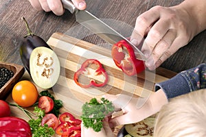 Food, family, cooking and people concept - Man chopping paprika on cutting board with knife in kitchen with daughter