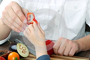 Food, family, cooking and people concept - Man giving paprika to the daughter