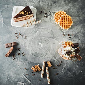 Food frame of chocolate milkshake with dripping sauce, cream, cake and cookie. Flat lay. Top view