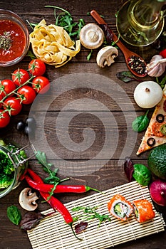Food frame made of vegetables, pizza, sushi rolls, tomato, pasta, olives and sauce on wooden background. Concept for menu. Flat la