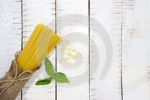Food frame. Pasta ingredients. Cherry-tomatoes, spaghetti pasta, garlic, basil, parmesan and spices on white background, copy sp