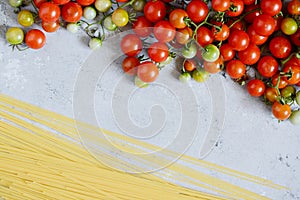 Food frame. Pasta ingredients concept. Uncooked spaghetti and cherry tomato on a blue background. Top view with copy space.