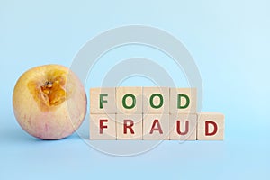 Food fraud concept. Rotten apple beside wooden blocks typography.