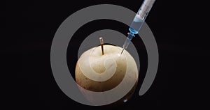 Food Genetic Modification - Syringle Injecting Liqquid in Apple. GMO Modification Concept.