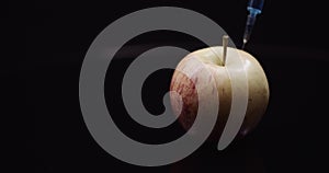 Food Genetic Modification - Syringle Injecting Liqquid in Apple. GMO Modification Concept.