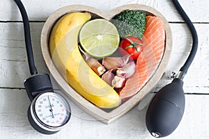 Food and healthy heart diet concept with blood preasure guage on white planks