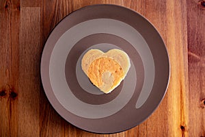 Food A heart-shaped pancake lies on a brown bench on a wooden table