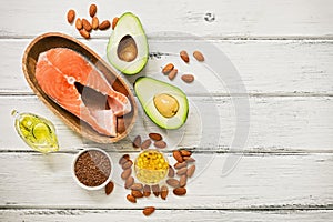 Food high in omega-3 fatty acids on a white wooden background. Healthy eating concept. Salmon, avocado, flax seeds, fish fat