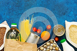 Food Home Delivery. Oil in a bottle, pasta, canned food, cereals, eggs, milk, fruits and vegetables on a blue rustic background.