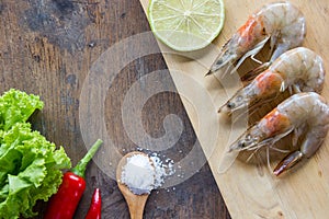 Food ingredient background. Shrimp, peppers, salad, salt , wood plate lime or lemon on table