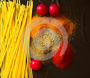 Food ingredients for italian pasta, spaghetti on black stone slate background.