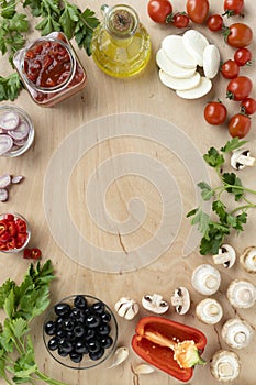 Food ingredients and spices for cooking italian pizza on wooden table - mushrooms, tomatoes, cheese, onion, oil, pepper, salt, bas