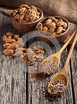 Food ingredients in wooden spoon on wooden background. Fiax, pumpkin seed, sunflower and sesame.