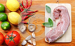 Food ingredients on wooden table in kitchen, meat on cutting board