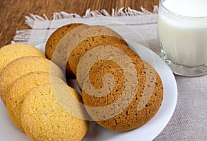 Food, junk-food, culinary, baking and eating concept - close up oatmeal cookies and milk glass