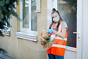 Teenagers deliver food to those in need. A young girl in a protective mask and medical gloves holds a basket of