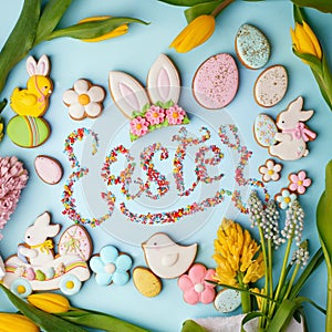 Food Lettering EASTER Colorful easter cookies and flowers tulip on blue background, assortment sweet gifts, seasonal springtime
