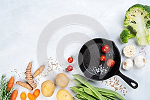 Food light background, iron skillet, vegetables, broccoli, tomato, green beans, potatoes, turmeric, carrot, garlic, cumin seeds,