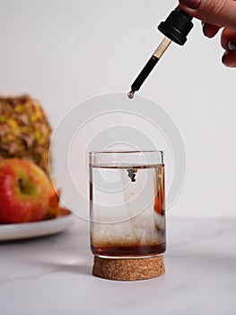 Food natural supplement liquid drops in glass of water with pipette, lifestyle