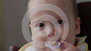 Food, nutrition, childhood concepts - close up Mom feeds infant baby with rubber spoon. Cute hungry child dressed in bib