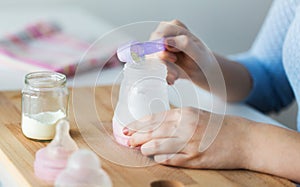 Hands with bottle and scoop making formula milk photo