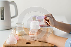 Hands with bottle and scoop making formula milk photo