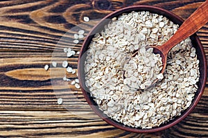 Food. Oatmeal on the table. Dry rolled oat flakes oatmeal in brown bowl on old wooden table.