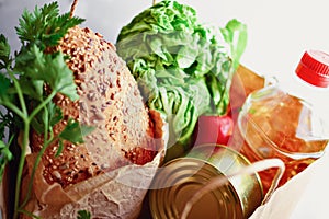 Food in a paper bag. Food donation or food delivery concept. Free space for text. Oil, bread, cabbage, salad, vegetables