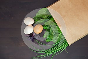 Food in a paper bag on a wooden table. Tomatoes, green onions, macaroni.