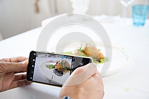 Food Photographer shooting food on phone`s camera photo