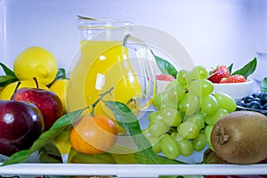 Food photography of a clean fridge filled with vegan foods such as fruits vegetables, juices and plant milk