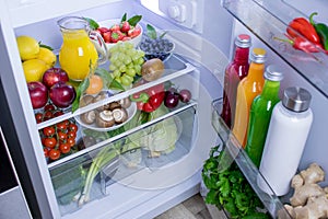 Food photography of a clean fridge filled with vegan foods such as fruits vegetables, juices and plant milk