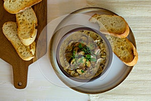 Food photography of a creamy mixed mushroom soup with herbs and toasted bread on a white surface