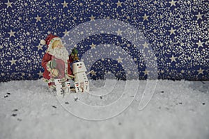 Christmas food photograph of marshmallows shaped as snowman in snow with stars pattern in background with Santa Claus decoration