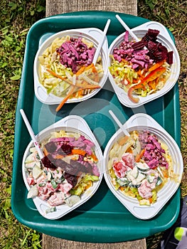 Food in plastic disposable bowls. Four bowls with different types of salad on the tray