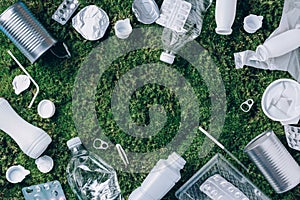 Food plastic packaging, trash on green moss background after picnic in forest. Top view. Copy space. Recycling plastic