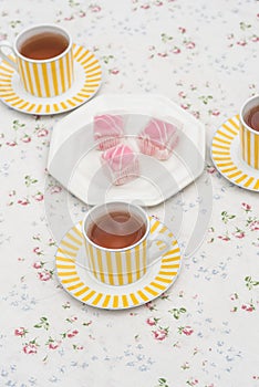 Food : Plate of pink iced sponge cakes and cups of tea. 2