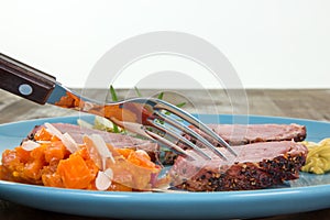 Food plate with roasted pork and vegetables on a brownish table i