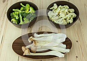 Food preparation on the bowls. The ingredients include fresh green broccoli, Pleurotus Eryngii, and Cauliflower