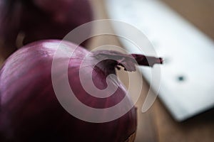Food preparation, cooking concept: fresh raw red onions, knife on a rustic wooden cutting board background