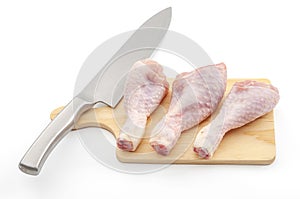 Food preparation, protein rich foods and healthy ingredients concept with raw chicken legs and knife on wood chopping board